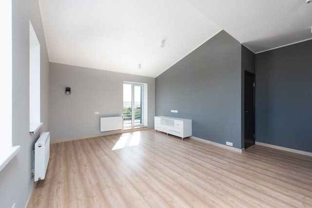 an unfurnished room with grey and blue walls and light wood floors